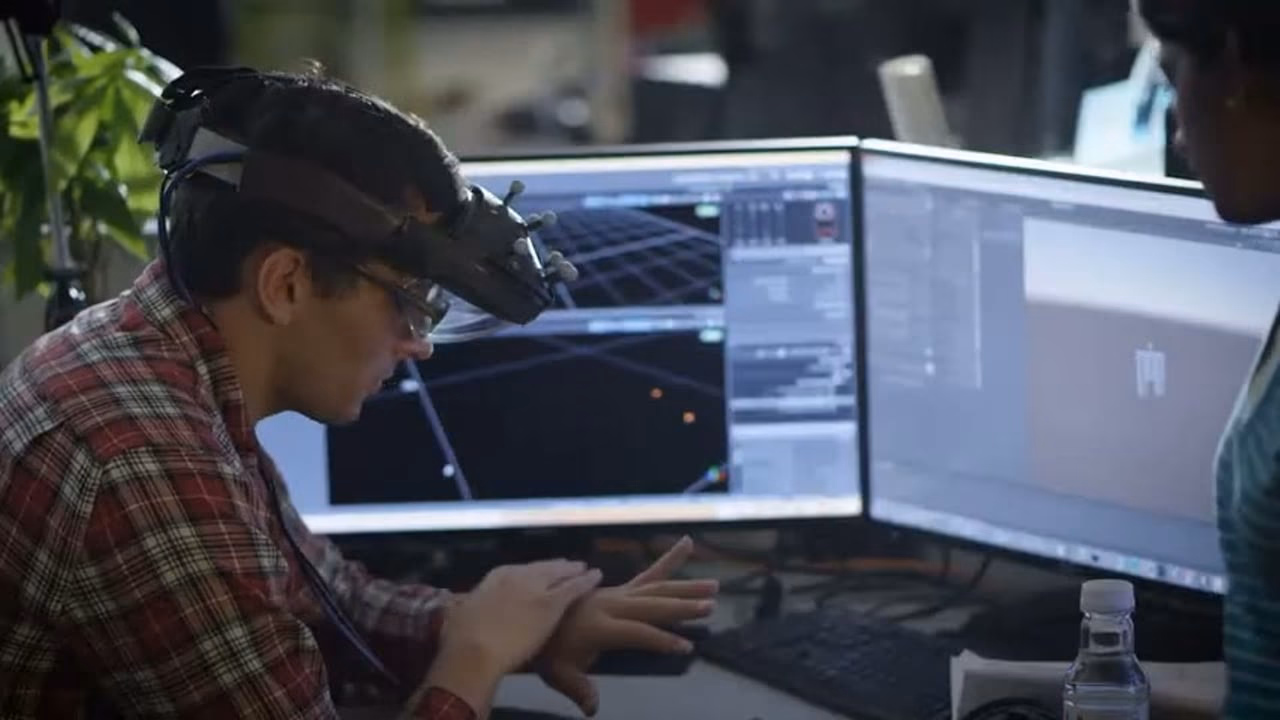 An engineer wearing the AR headset while working across two monitors